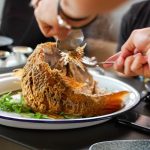 Man Holding Whole Fish With Forks